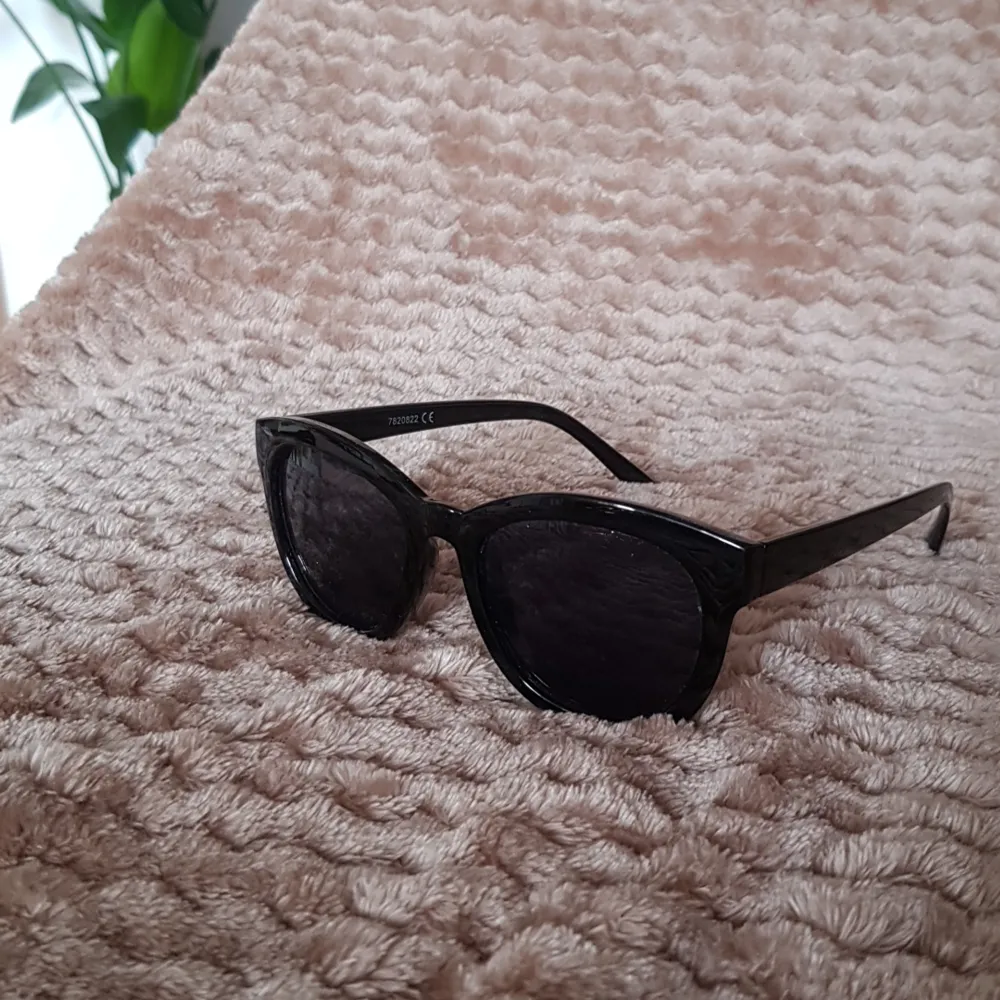 Svarta blanka solglasögon med svart glas. Accessoarer.