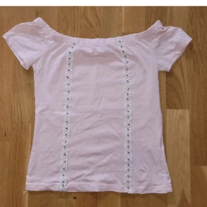 T-shirt  - Skitgullig off-shoulder topp med detaljer. I jättebra skick. Det står storlek S/M, men skulle säga att den passar XS oxå. Kan fraktas, men köparen står för frakten💕