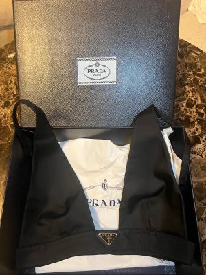 Prada re-nylon topp  - Oanvänd PRADA Re nylon topp i svart. Stl 38 ( som en 36a)  Jätte eftertraktad topp finns ej tillgänglig i denna Stl. 