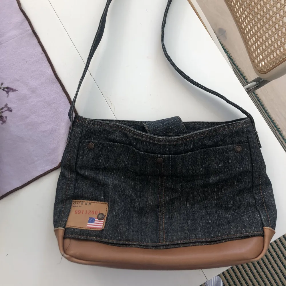 Handväska från Guess i jeanstyg med bruna detaljer. Många fickor och utrymme! . Väskor.
