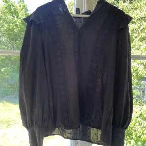 Svart mönstrad blus  - En jättesnygg svart blus med mönster på. Blusen är gjort på ett genomskinligt tyg men man ser inte igenom (se bild 1).   Blusen är perfekt till alla tillfällen, en middag, skolan eller en fest.  Storlek L, passar M också  