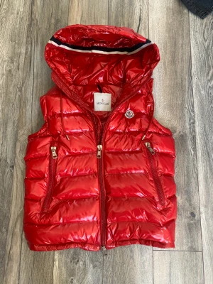 Moncler Väst - Äkta Moncler väst, Fin väst i bra skick. Ända är att den har ett litet snitt (Sista bilden). Storlek 2/M. Säljer den billigt för skadan och för jag ej har kvitto