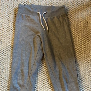 Mjukisbyxor - Gråa mjukisbyxor med röd, vit och svarta stripes på sidorna. 