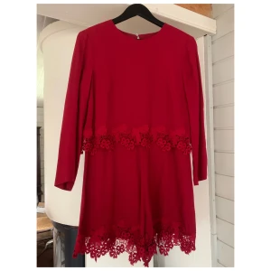 Röd playsuit med spets - Röd playsuit/byxdress med spetsdetaljer. Storlek 40, sparsamt använd. Fint skick.