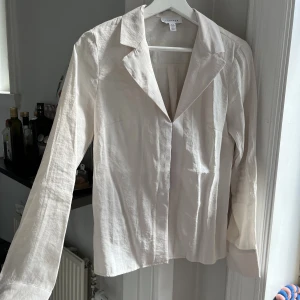Benvit blus  - Helt oanvänd!!! Blus med krage och ”hakar” istället för knappar! Storlek 36 men passar mig som brukar ha 38