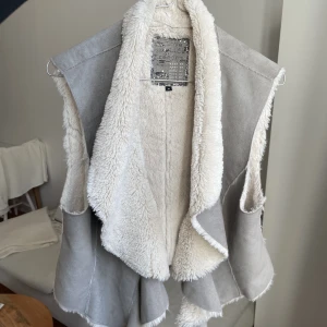 Väst - Mocka väst med fejkpäls. Köpt second hand men riktigt fint skick! Står ej storlek men jag har S och den passar toppen