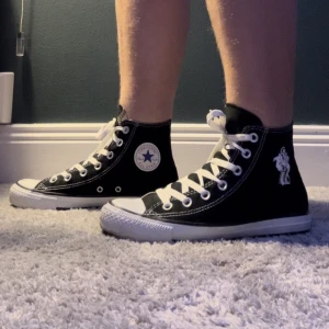 Svarta converse  - Svarta converse med vad jag tror är pirates of the Caribbean tryck på ena sidan. Jättefint skick. Storlek 36.5