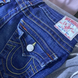  True religion jeans -  True religion jeans som är mörkblå och låg midjade Som är i storlek 25 som motsvarar ungefär storlek S och passar mig som har storlek S de har ett litet osynligt hål det är bara en liten sömn som har öppnat upp sig Lite men är osynlig