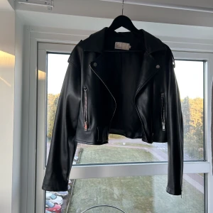 Skinnjacka  - Skinnjacka i fint skick (inte äkta skinn). Jackan slutar ovanför rumpan. 