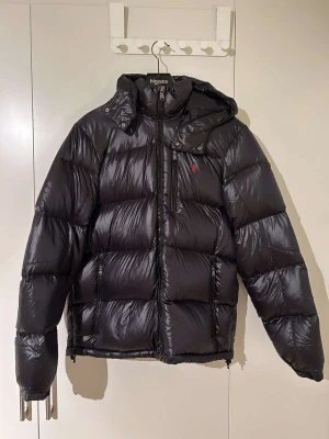 Polo Ralph Lauren Dunjacka - Black Glossy  - Säljer min Ralph Lauren jacka eftersom att jag har köpt en ny jacka som kommer att användas istället för denna. Änvänt runt 3 gånger, nytt skick.