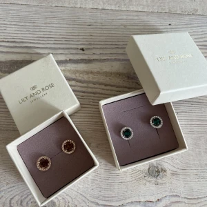 Lily and Rose örhängen  - Helt nya örhängen från Lily and Rose i modellen Miss Miranda. Ett par är med grön Sten och ett med orange/ bronze färgad Sten. Nypris är 329kr/st. Säljer för 200kr/st. Postar för 15kr