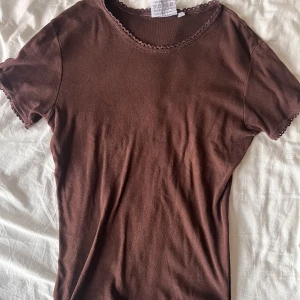 Brun t-shirt med spets - Jättesöt t-shirt köpt second hand, bra skick men sömmen längst ner är lite skadad. Kom privat om du vill ha fler bilder på det. 
