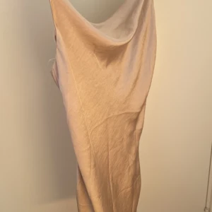 Kort silkes klänning  - Champagnefärgad silkesklänning från Ginatricot i storlek S. Klänningen har spännbara band och extra tyg inuti vid bysten samt vattenfallurringning. Klänningen är kort. Den är aldrig använd då den är för liten för mig.