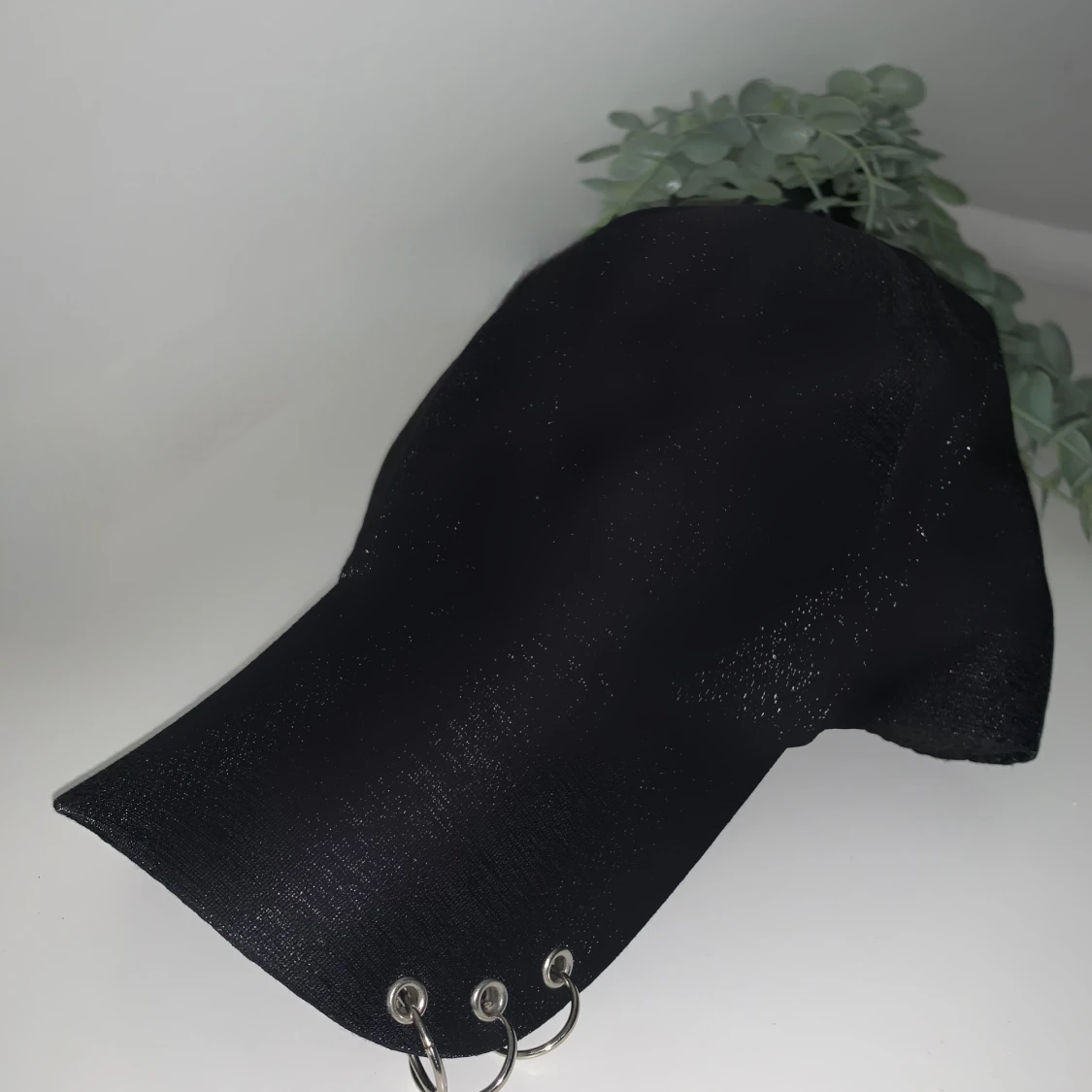 Svart keps med metallringar