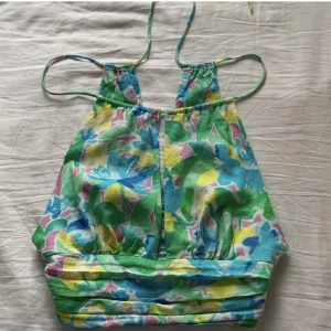 Halterneck-topp - Färgglad samt blommig halterneck köpt ifrån Bershka 🍓Använd vid ett fåtal tillfällen och är i fint skick. Orginalpris: 259 kr