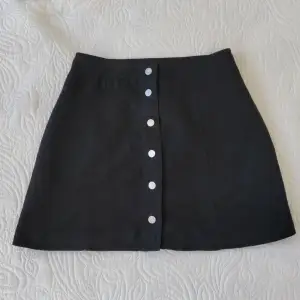 Svart kort kjol med silver tryckknappar från H&M