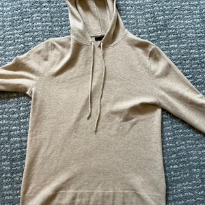 Kashmir hoodie från Ralph Lauren - Säljer en lyxig beige hoodie från Ralph Lauren i 100% kashmir. Den har en klassisk design med huva och dragsko, perfekt för en stilren och bekväm look. Passar utmärkt för kyligare dagar.