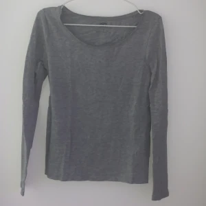 Grå långärmad tröja från 157 - Säljer en enkel och stilren grå långärmad tröja från 157. Perfekt för en avslappnad look. Tröjan har en rund halsringning och är tillverkad i ett mjukt material.