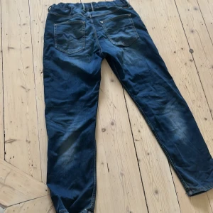 Blå jeansbyxor med elastisk midja - Säljer ett par blå jeansbyxor med elastisk midja och klassisk femficksdesign. Byxorna har en broderad detalj på bakfickan och är tillverkade i denim. Perfekta för en avslappnad stil.Har en liten defekt på höger bakficka. Storlek 164 men passar lätt XS och S. Nypris ca 700 kr.