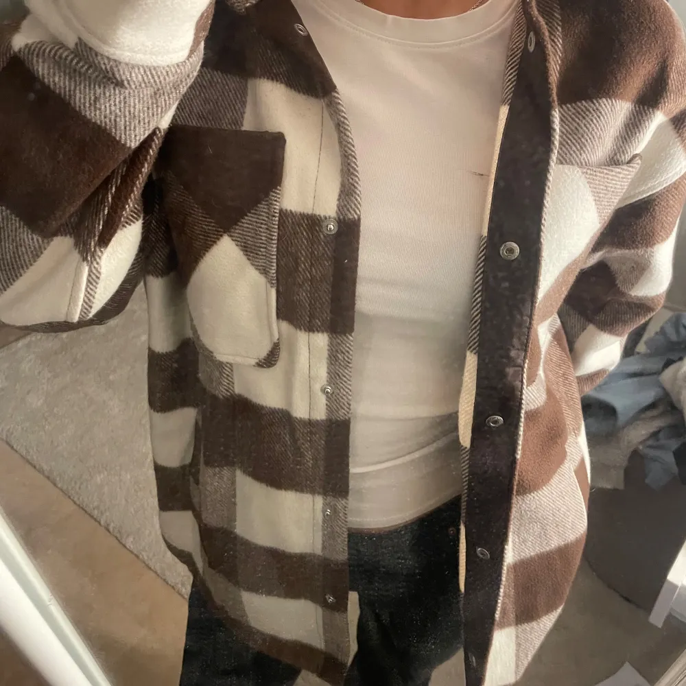 Säljer en snygg brun och vit rutig overshirt med knappar. Perfekt för lager på lager-stil. Den har långa ärmar och en bröstficka för extra stil och funktion💋Tydligen i storlek XXS men passar mig som vanligtvis har S på jackor. Takit.
