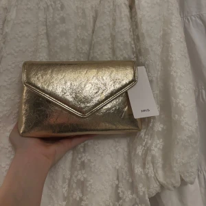 Guldig clutch från mango!! - Snygg guldig  clutch  från  mango helt ny med lappen kvar, perfekt för tex bal!!