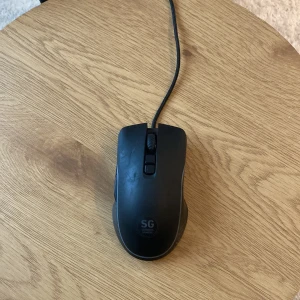 Svart datormus från SG - Säljer en svart datormus från SG med sladd. Musen har en enkel och stilren design med två knappar och ett scrollhjul. Perfekt för både arbete och spel.