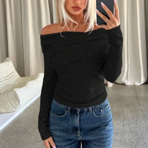Svart offshoulder topp - Snygg svart offshoulder topp med långa ärmar. Perfekt för en stilren look. Tillverkad i ett mjukt och bekvämt material som sitter skönt mot huden. 