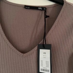Beige ribbad klänning från lager 157 - Snygg beige ribbad klänning från lager 157 i storlek XS. Klänningen har en v-ringad hals och långa ärmar med en liten slits (Mina bilder). Andra bilden är en referens för passformen men annan färg. Aldrig använd med prislapp kvar.🤎 Säljs för 150kr men priset kan diskuteras.
