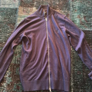 Mörkblå tröja med dragkedja från J.Lindeberg - Säljer en stilren mörkblå tröja från J.Lindeberg med dragkedja framtill. Tröjan har långa ärmar och ribbade muddar vid ärmslut och nederkant. Perfekt för en avslappnad men snygg look. Tröjan är liten och passar bättre till storlek S än M