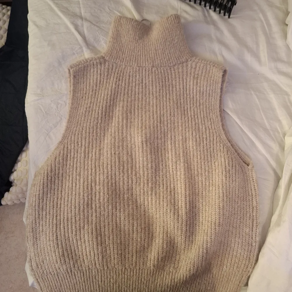 Säljer en mysig beige stickad väst från Lindex. Västen har en dragkedja framtill och en hög krage. Passar barn i storlek 146/152.. Neuleet.