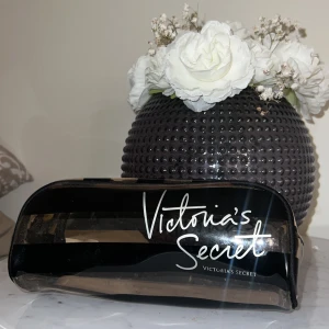 Necessär  från Victoria's Secret - Snygg necessär från Victoria's Secret i svart och beige med dragkedja. Perfekt för att förvara smink eller andra småsaker. Den har ett stilrent randigt mönster och är lätt att ta med sig.