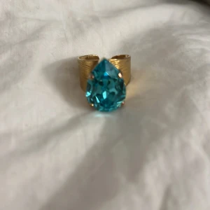 Classic Drop Ring / Aquamarine i guld    - Snygg guldfärgad ring från Caroline Svedblom med en stor, droppformad sten i aquamarine. Säljer då jag har två nu.
