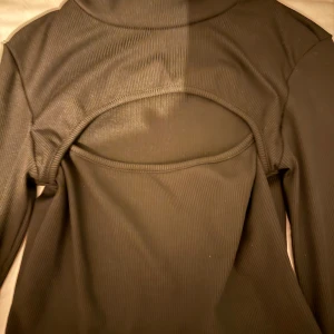 Svart ribbad topp från SHEIN - Snygg svart ribbad topp från SHEIN med lång ärm och en öppen ficka fram. 