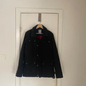 Svart jacka från J.Lindeberg - Snygg svart fieldjacka från J.Lindeberg med knappar och dragkedja. Perfekt för kyligare dagar med sin stilrena design och praktiska detaljer. Passar storlek L perfekt. Skriv om ni har några fler frågor🙌