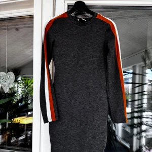 Grå klänning med färgade ränder - Snygg grå klänning med långa ärmar och färgade ränder i orange och vitt längs ärmarna. Rensar ur min garderob från en hel del kläder🌼 Om du ser något mer i min profil som du gillar så skickar jag med det till dig också!😊 Fler kläder kommer! 