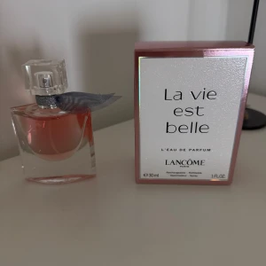 Parfym Lancôme - Säljer en elegant flaska av La Vie Est Belle Eau de Parfum från Lancôme. Flaskan har en stilren design med en klar glasflaska och en liten rosett vid halsen. oanvänd