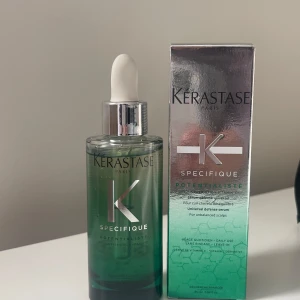 Kerastase Specifique Potentialiste Serum - Säljer ett Kerastase Specifique Potentialiste serum. Flaskan är grön med en pipett för enkel applicering. Förpackningen är elegant med en metallisk finish. Perfekt för att balansera hårbotten och ge näring.