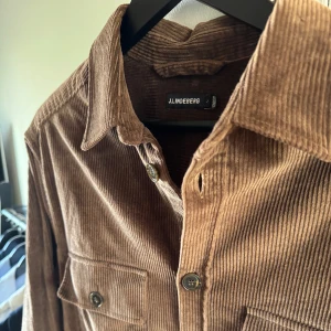 Brun manchester overshirt från J.Lindeberg - Riktigt fet brun manchester overshirt från J.Lindeberg i storlek L. Bara använd ett fåtal gånger och är i mycket bra skick! Perfekt för lager-på-lager-stil till både sommaren och vintern. Ordinarie pris är 1800. Hör av er vid fler frågor, pris kan diskuteras!