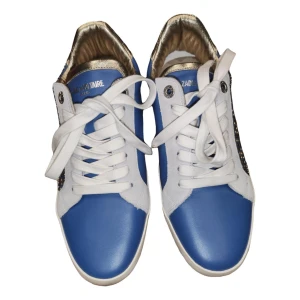 Blå och vita sneakers från Zadig & Voltaire - Snygga sneakers i blått och vitt med gulddetaljer från Zadig & Voltaire. Skorna har snörning och är dekorerade med små nitar på sidorna. Perfekta för en trendig look.