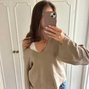 Beige v-ringad tröja - Säljer en beige v-ringad tröja från NA-KD med långa, vida ärmar och avslappnad passform. Tröjan är stickad och har en snygg oversized look som passar perfekt till jeans eller kjol. Superenkel att styla för en chill vibe.