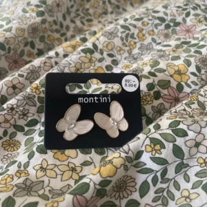 Vita fjärilsörhängen från Montini - Supersöta örhängen från Montini i form av vita fjärilar med guldkant och en liten pärldetalj i mitten. Perfekta för att ge din look en gullig och trendig touch. Stift i guldton och smidig storlek som passar till allt.