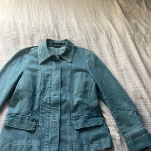 Jeansjacka från Prêt à Porter, stl 40 - Snygg jeansjacka från Prêt à Porter i klassisk blå denim. Jackan har krage, fyra fickor framtill och markerade sömmar som ger en schysst siluett. Perfekt för dig som gillar en tidlös och avslappnad look. Långärmad och stängs med knappar framtill. har också dragekedja 