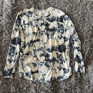 Blåvit tie-dye långärmad tröja Hollister - Säljer en långärmad tröja från Hollister med blå och vit tie-dye mönster. Tröjan har rund halsringning, tryckt logga på bröstet och text längs båda ärmarna. Även tryck på ryggen. Skön och avslappnad passform, perfekt för en chill look. Tröjan är använd, så den har noppor på sig (se bilder)