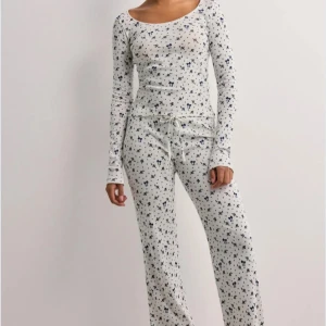 Vita mjukisbyxor med blått mönster - Supermysiga vita mjukisbyxor med blått stjärnmönster och snörning i midjan. Byxorna har en relaxed passform och är perfekta för chill dagar hemma. Tillverkade i mjukt bomullsmaterial för extra komfort.