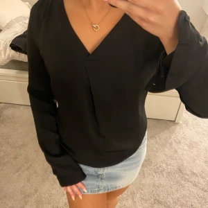 Svart v-ringad blus med knappar - Snygg svart blus med v-ringning och långa ärmar. Perfekt att styla med jeans eller kjol. Går att stänga vid handleden ville bara visa den lösa tråden. Tror man bara kan klippa av den tbh☺️ Förutom det så en den i fint skick! 