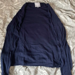 Mörkblå långärmad tröja  - En enkel och stilren mörkblå långärmad kofta från Lager 157. Tröja är tunn och har en rak passform, perfekt att slänga över en t-shirt eller linne. Tillverkad i mjukt bomullsmaterial som känns skönt mot huden.