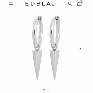Silvriga örhängen från Edblad - Säljer billigt vid snabb affät!!Snygga silvriga örhängen från Edblad med minimalistisk design. De har runda hoops och en hängande konformad detalj som ger en cool och modern vibe. Perfekta för att lyfta din stil med en edgy touch. Box ingår om man vill (skriver priv)