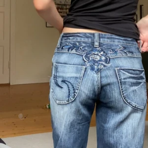 Blå bootcut jeans med broderi - Säljer ett par blå bootcut jeans med snyggt broderi och detaljerade sömmar på bakfickorna. Jeansen har låg midja. Y2k!!