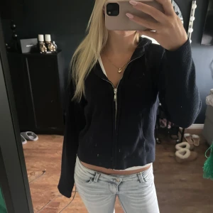 Mörkblå stickad zip-hoodie - Mysig mörkblå stickad hoodie med dragkedja framtill och huva. Jackan har långa ärmar och en croppad passform som ger en chill vibe. Perfekt att slänga på sig över ett linne eller t-shirt. Snyggt ribbstickat material som känns både mjukt och stilrent.