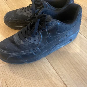 Svarta Nike Air Max sneakers - Säljer ett par helsvarta Nike Air Max sneakers med klassisk siluett. Skorna har mesh och skinnpaneler, synlig Air Max-dämpning i sulan och snörning framtill. Pris kan diskuteras 